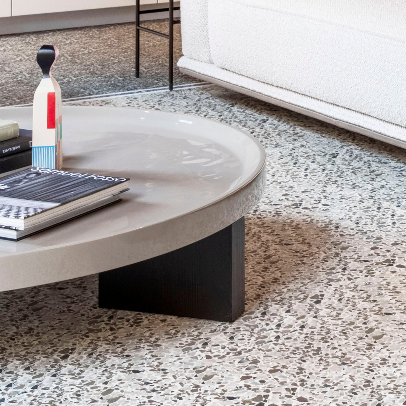 Tavolino Louver di Minotti con piano beige, con complementi e libri fotografici, di fronte a un divano in showroom SAG'80.