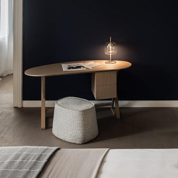 Scrittoio Sidus di Arflex con piano curvo in rovere chiaro, con lampada da tavolo e pouf in area notte di showroom SAG'80.