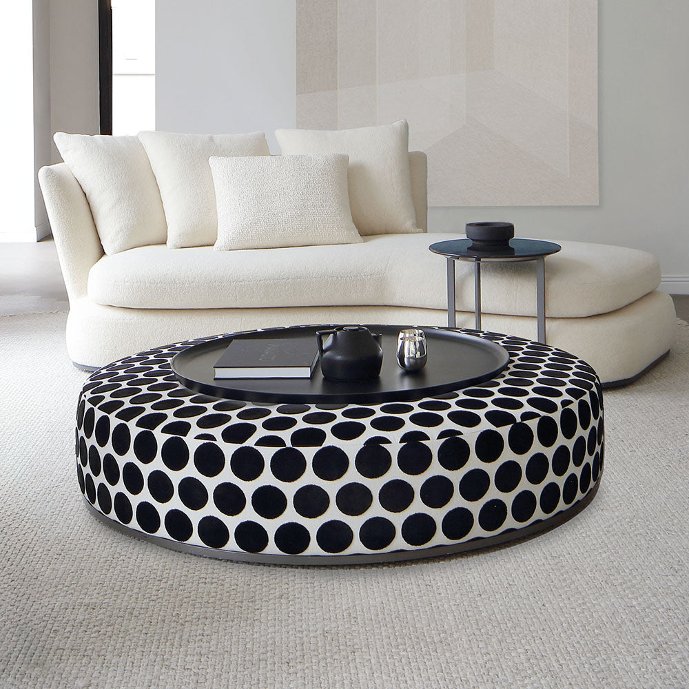 Pouf Amoenus di Maxalto grande, con tessuto a pois neri su bianco, di fronte a divano in area living di showroom SAG'80.