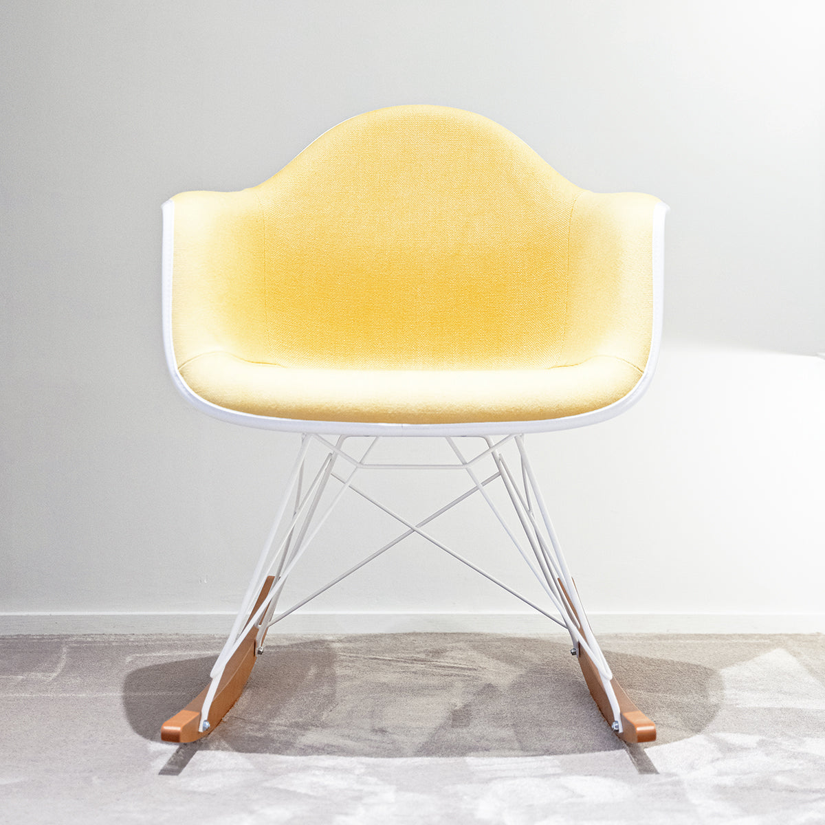 Vitra Eames Plastic Chair RE RAR con scocca bianca rivestita in tessuto giallo e struttura bianca, in angolo di showroom SAG'80 Selection. 