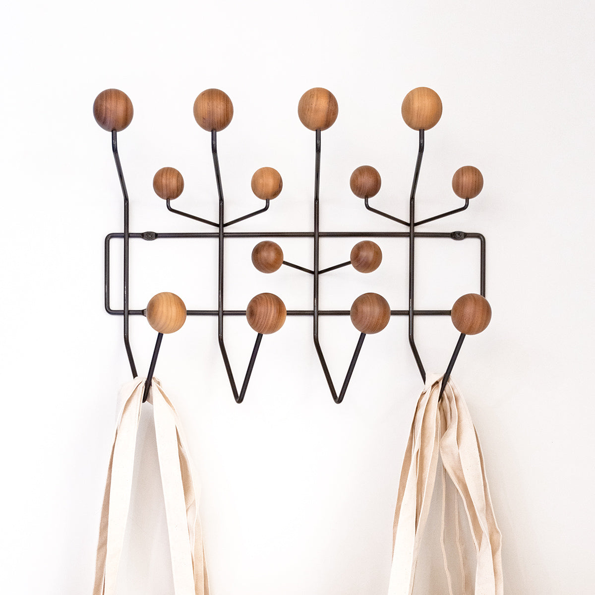 Vitra Hang it All con pomelli in legno e struttura nera su parete bianca. 