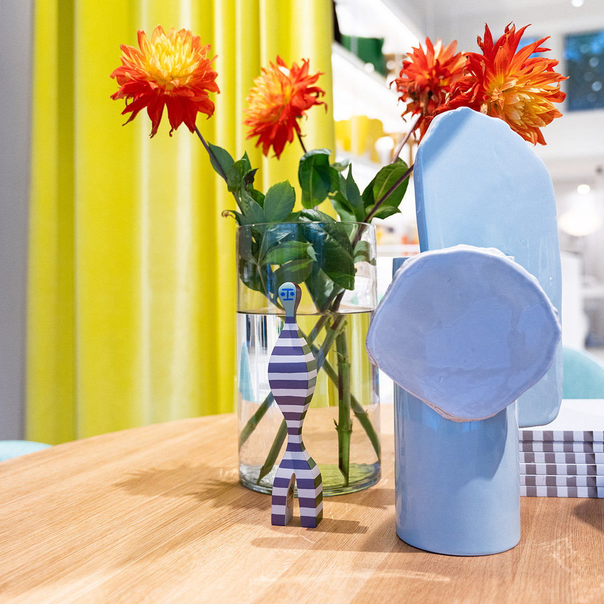 Vitra Wooden Doll in sfumature blu, su tavolo di legno con vasi e fiori in showroom SAG'80 Selection.